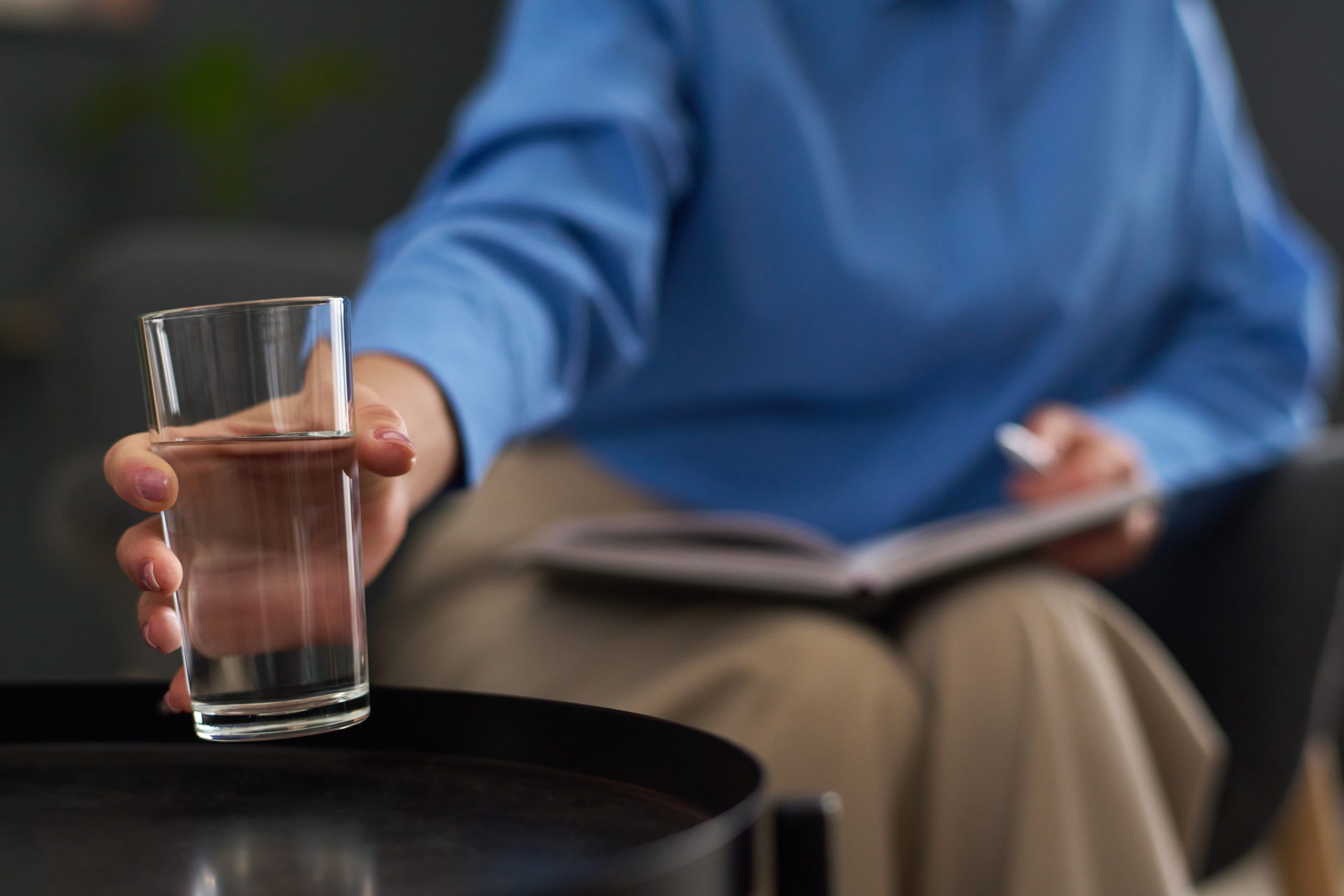 A hand extending a glass of water — the offering of care