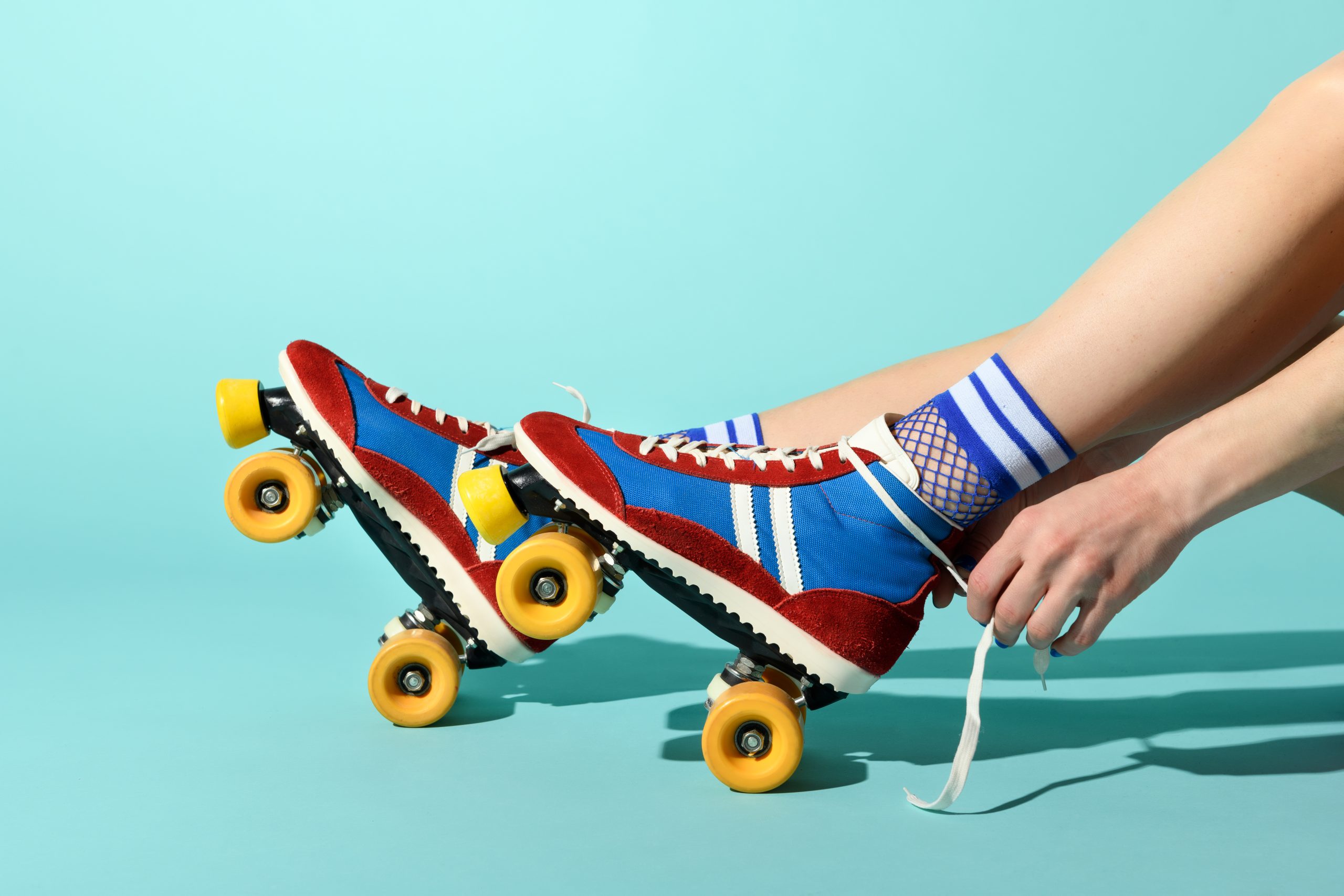 A woman putting on roller skates and tying the laces